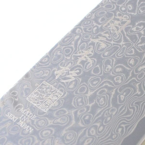 A kitchen knife focusing on its logo on the Damascus blade