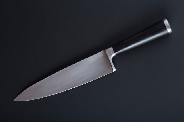 An image of a chef's knife placed diagonally against a black background.