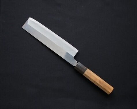 An image of a vegetable knife displayed diagonally against a black background.