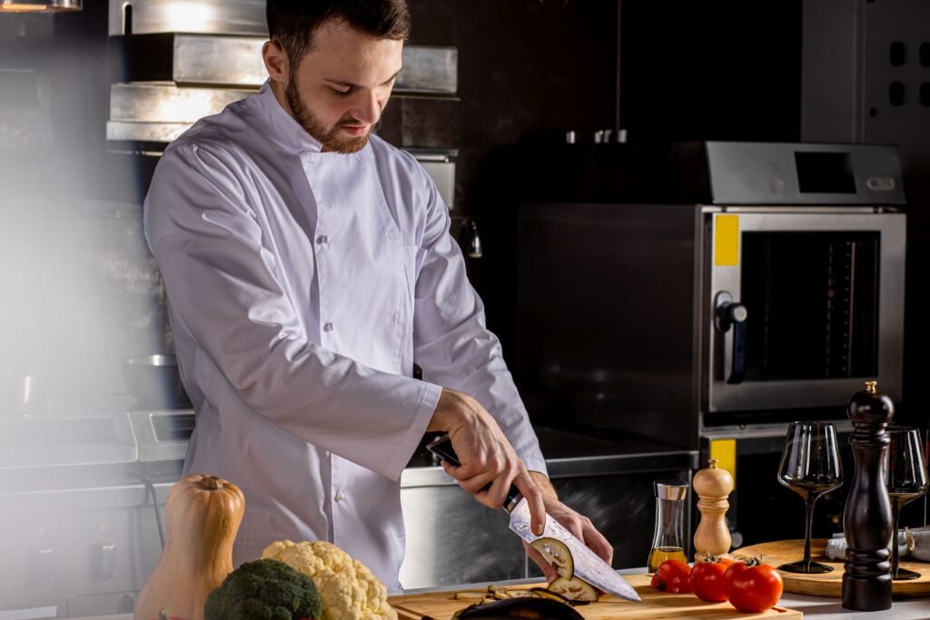 A male chef slicing a vegetable in a kitchen