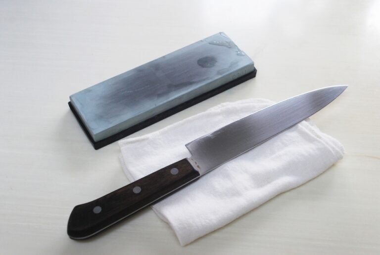 A kitchen knife placed on a white towel next to a whetstone