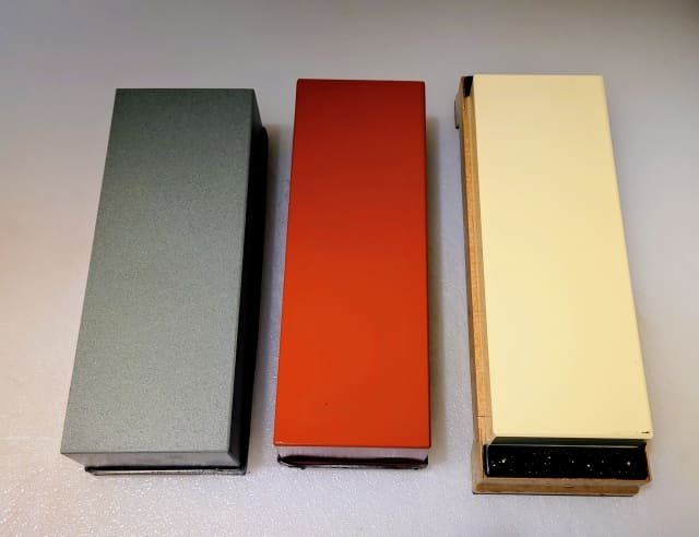 Three whetstones placed side by side with coarse, medium, and finishing grits.