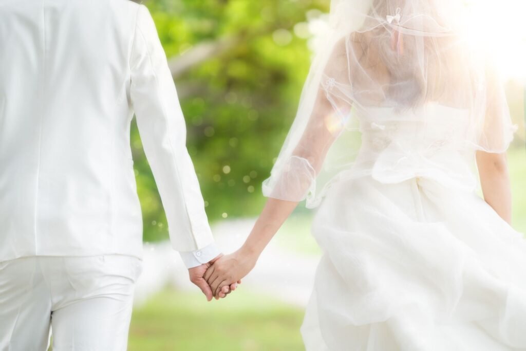 a rear view of a bride and groom holding hands at their wedding