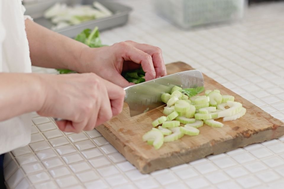 A person chopping vegetables on a wooden chopping board.