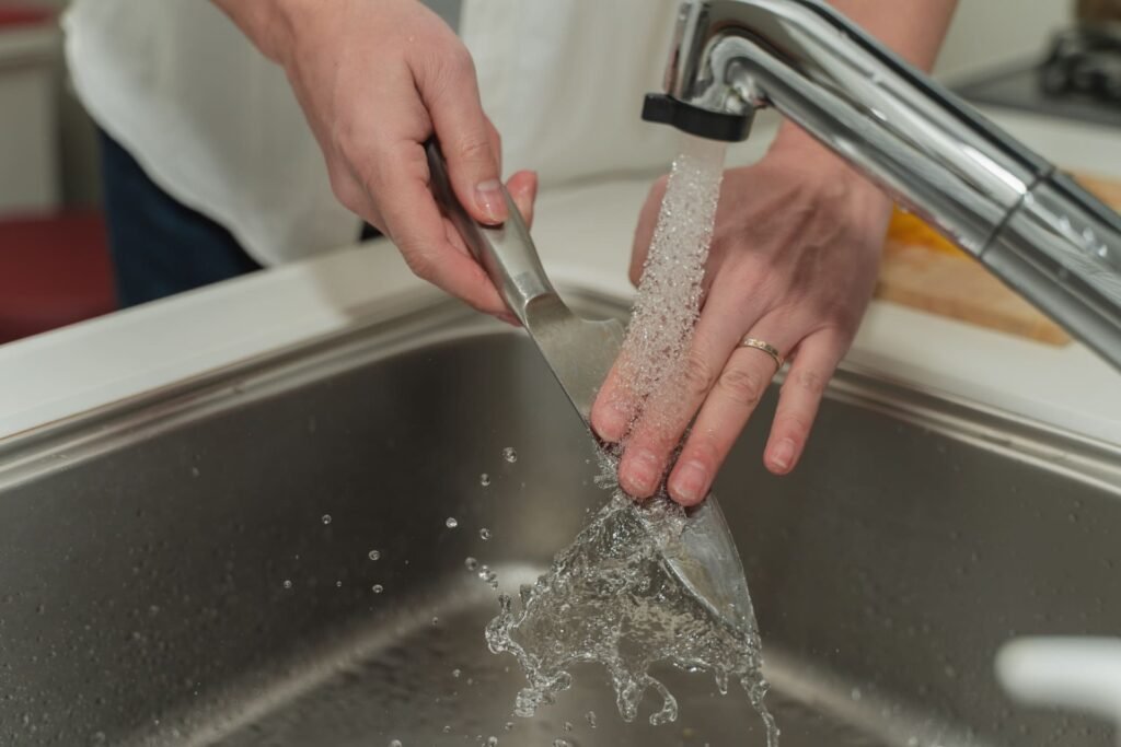 washing a kitchen knife by hand in the sink