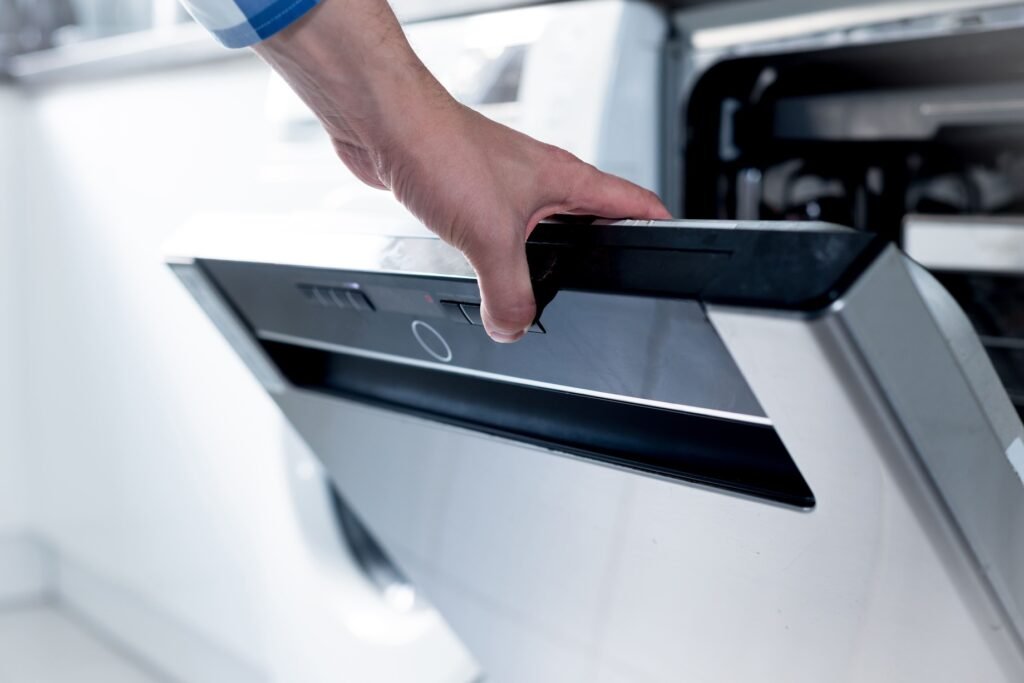 a hand opening a dishwasher door