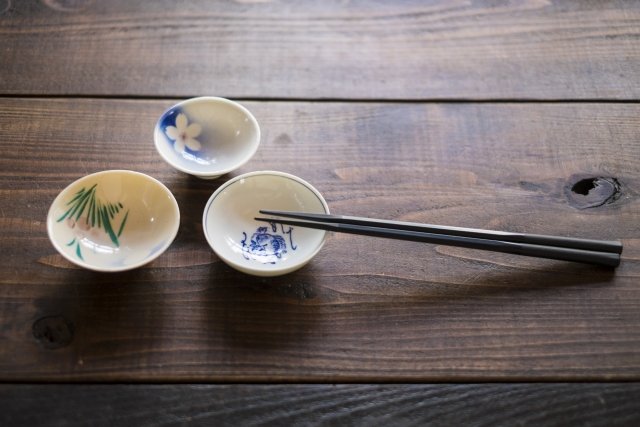 Three mamezara plates with a single pair of chopsticks resting on them.