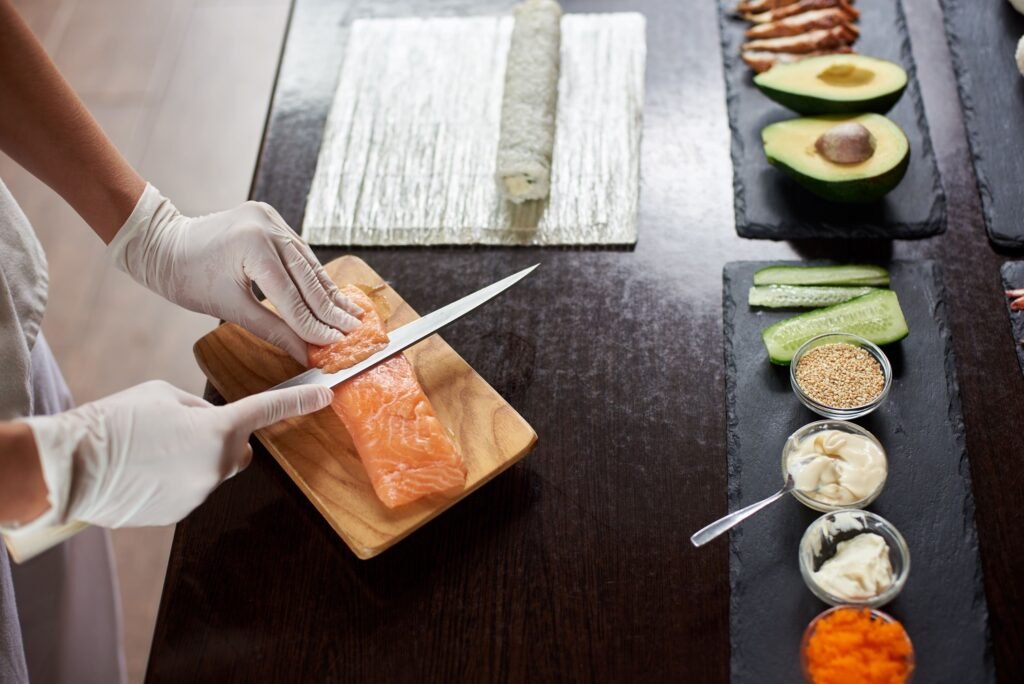 Chef Preparing Sashimi with Salmon and Sushi Ingredients Nearby