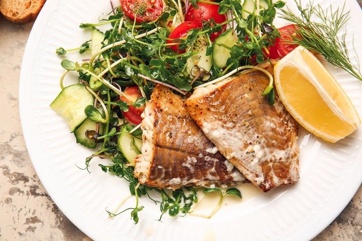 Pan-fried fish with green salad on a plate